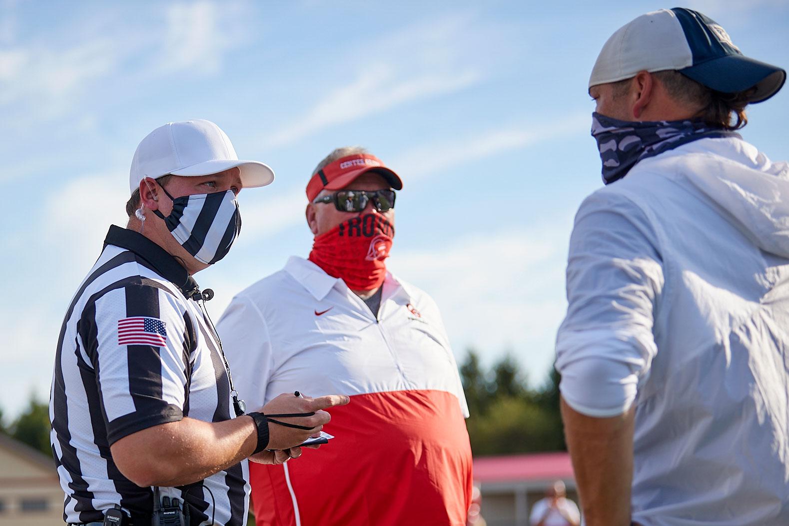 Image of a meeting between an official and coaches before a game.
