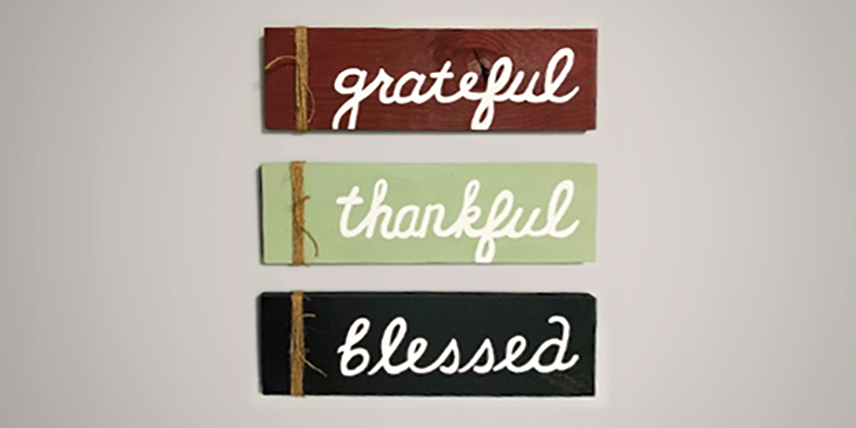 Image of three signs hanging on a wall, reading: Grateful - Thankful - Blessed.