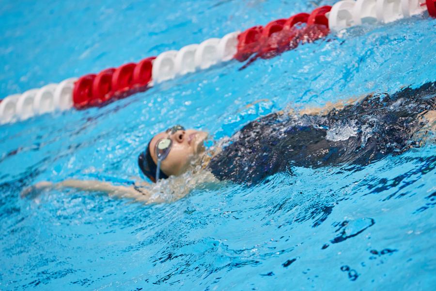 A girl does a backstroke in a pool